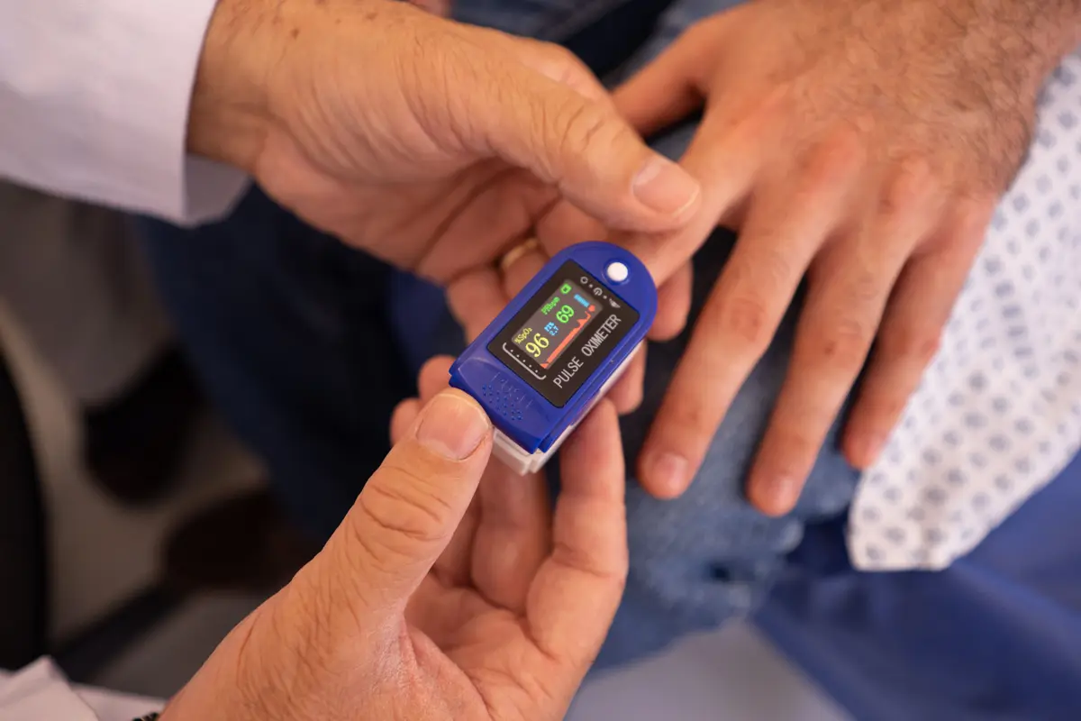 Control de saturación con oxímetro de pulso en la mano de un paciente
